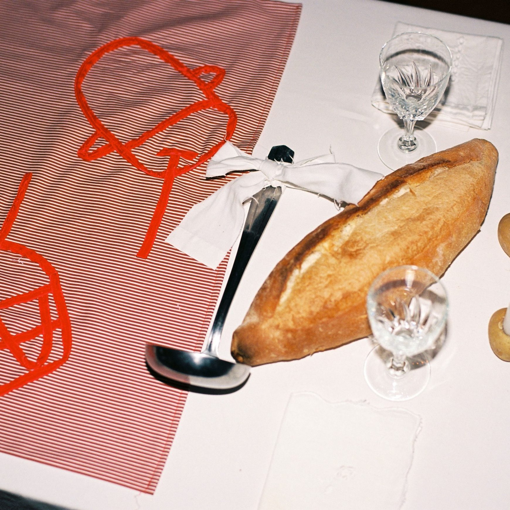 Festa, premier repas autour du keşkek, 14 septembre 2023, Marseille, détail : table, nappe brodée avec des rubans en velours, ustensiles, pain et bougies © Emma Tholot